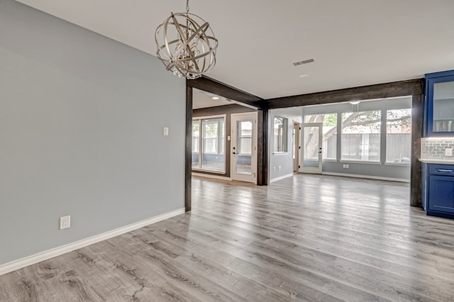 interior space featuring visible vents, baseboards, light wood finished floors, and a notable chandelier