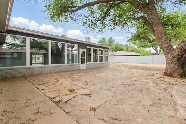 back of house featuring brick siding, fence, a chimney, and a patio