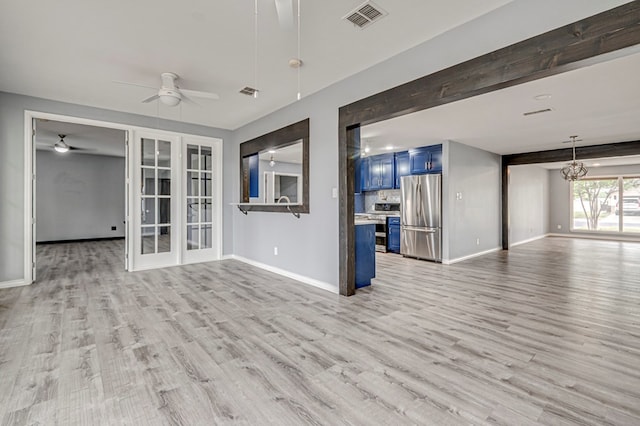 unfurnished living room featuring light wood-style floors, baseboards, ceiling fan with notable chandelier, and visible vents