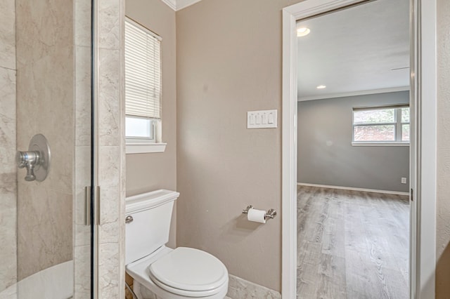 full bath featuring toilet, baseboards, wood finished floors, ornamental molding, and a stall shower