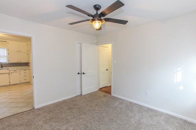 unfurnished bedroom featuring sink, ceiling fan, connected bathroom, and light colored carpet