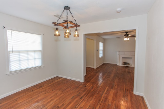 unfurnished dining area featuring ceiling fan, dark wood-type flooring, and plenty of natural light