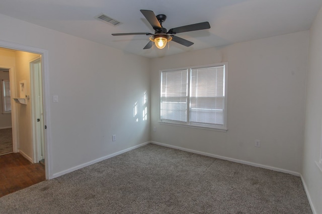 spare room featuring dark colored carpet and ceiling fan