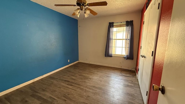 empty room with a textured ceiling, ceiling fan, wood finished floors, and baseboards