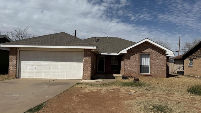 ranch-style house with an attached garage, brick siding, concrete driveway, and roof with shingles