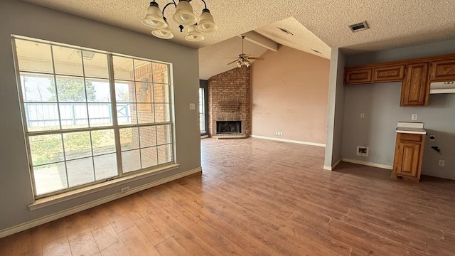 unfurnished living room with a healthy amount of sunlight, light wood-style floors, a fireplace, and a textured ceiling