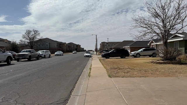 view of street with sidewalks, street lighting, a residential view, and curbs