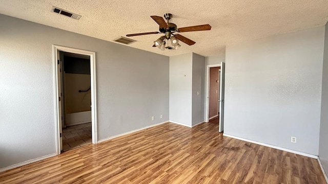 empty room with ceiling fan, visible vents, and wood finished floors