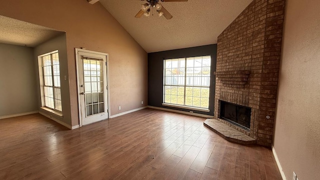 unfurnished living room featuring lofted ceiling, a textured ceiling, a fireplace, and wood finished floors