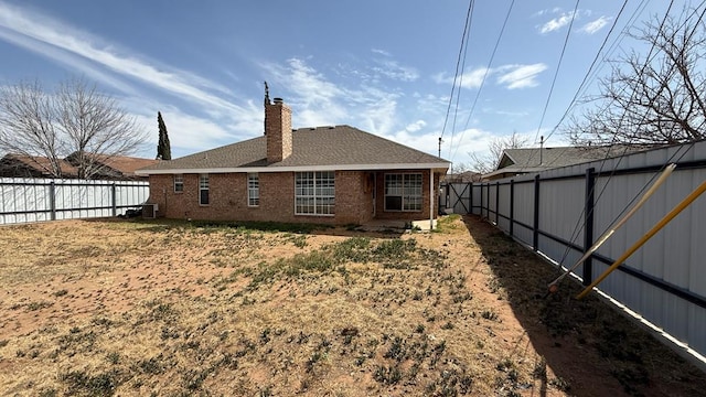 back of house featuring brick siding, roof with shingles, a chimney, and a fenced backyard