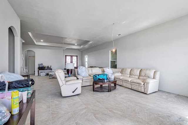 living room featuring a raised ceiling and arched walkways