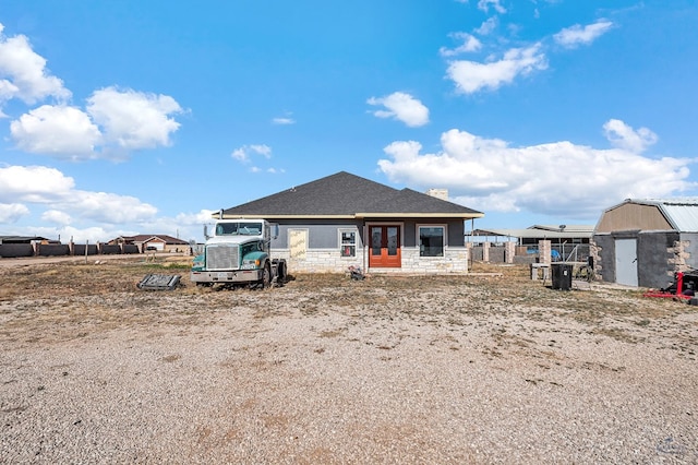 back of property with french doors, stone siding, a chimney, and fence