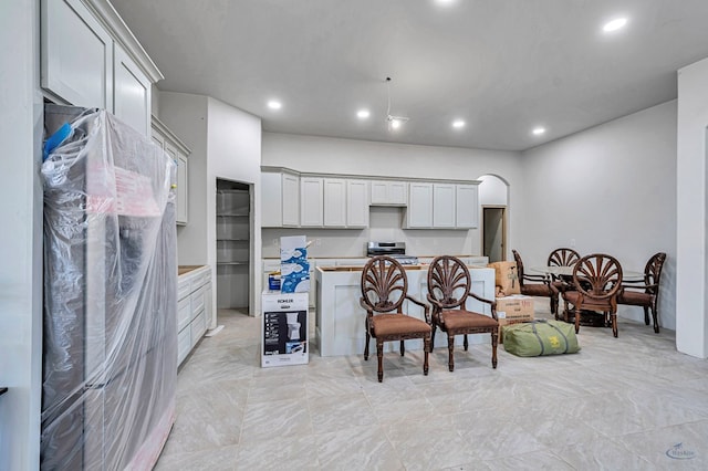 kitchen featuring arched walkways, recessed lighting, stainless steel range, and light countertops