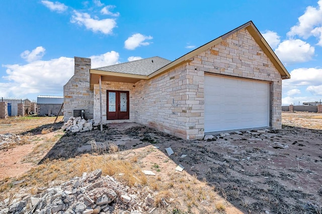 view of front of house featuring a chimney, french doors, a shingled roof, and a garage