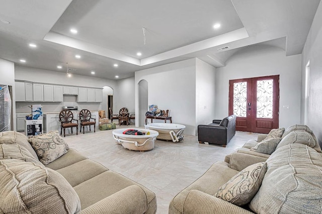 living room with visible vents, recessed lighting, arched walkways, french doors, and a raised ceiling