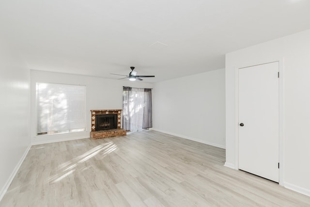 unfurnished living room with ceiling fan, light wood-type flooring, and a brick fireplace