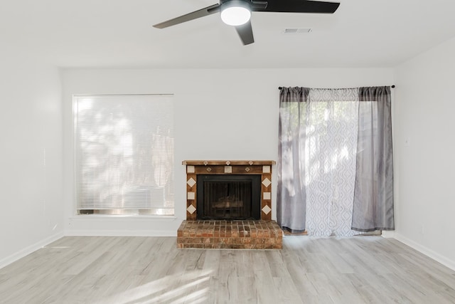 unfurnished living room featuring ceiling fan, light hardwood / wood-style floors, and a brick fireplace