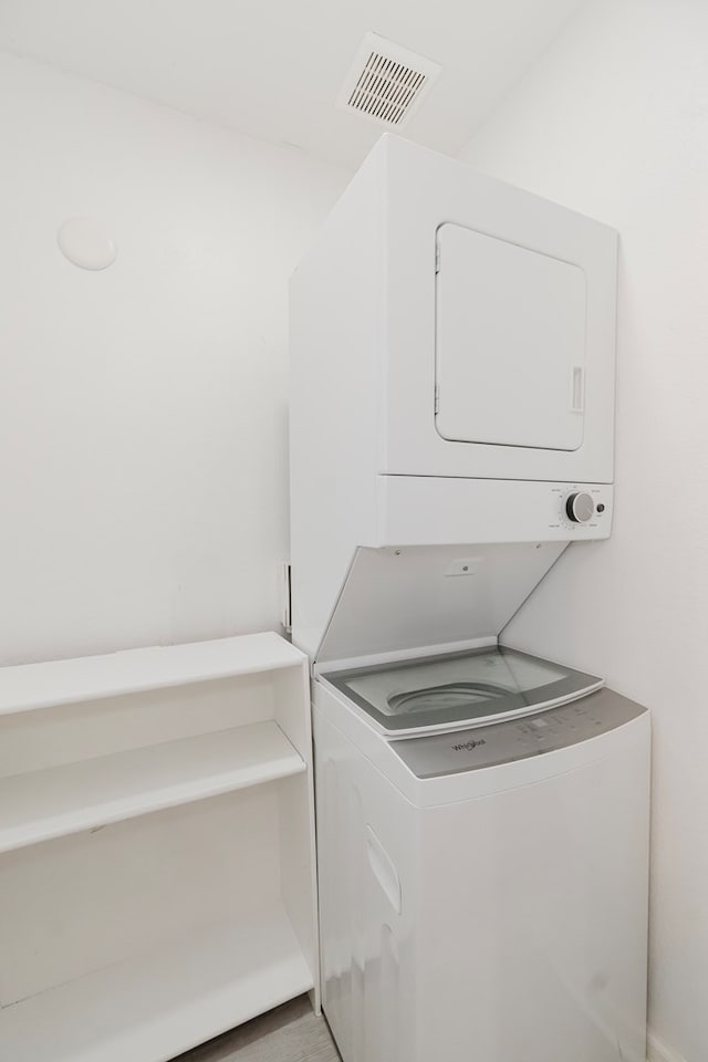 clothes washing area with stacked washing maching and dryer