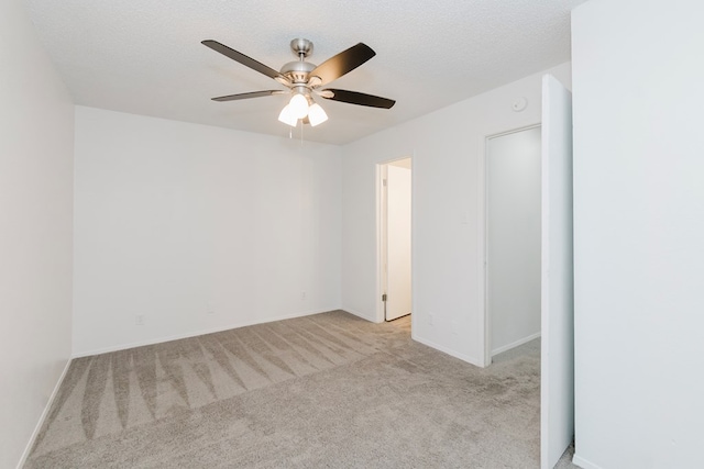 spare room featuring ceiling fan, light colored carpet, and a textured ceiling