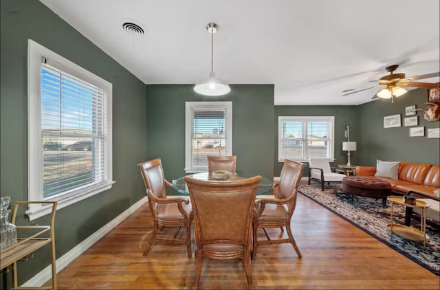 dining room with baseboards, visible vents, ceiling fan, and wood finished floors