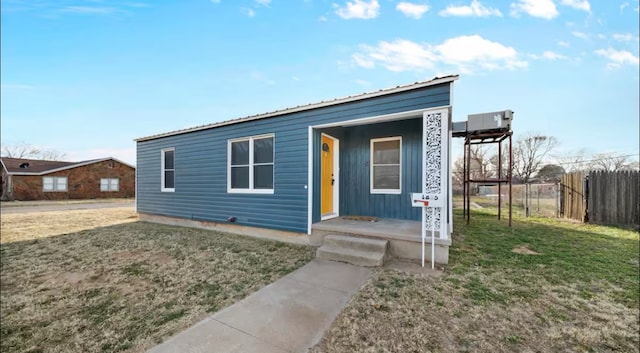 view of front of home featuring metal roof, fence, and a front lawn