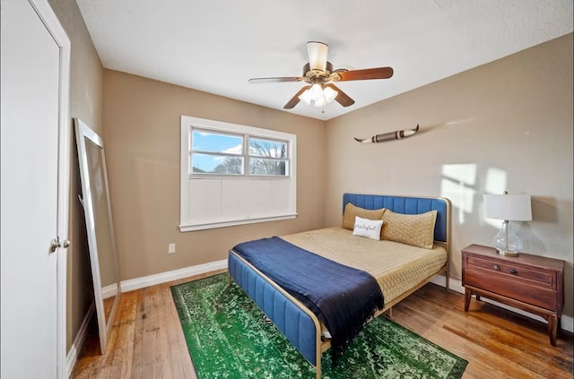 bedroom with a ceiling fan, baseboards, and wood finished floors