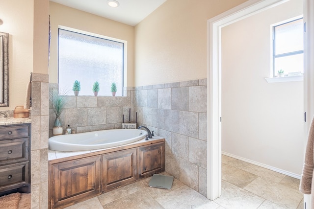 bathroom featuring vanity, a bath, and tile walls