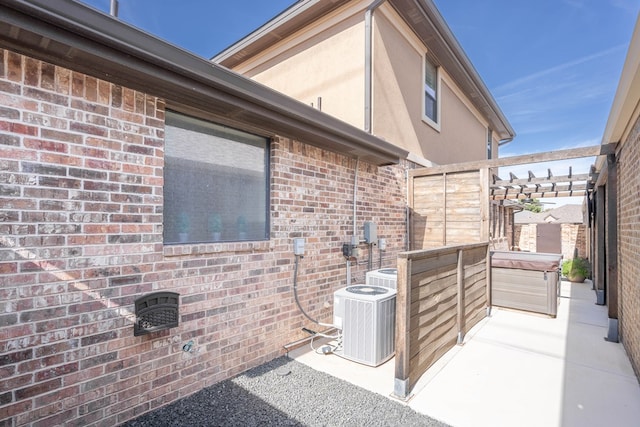 exterior space featuring a hot tub, a patio, cooling unit, and a pergola