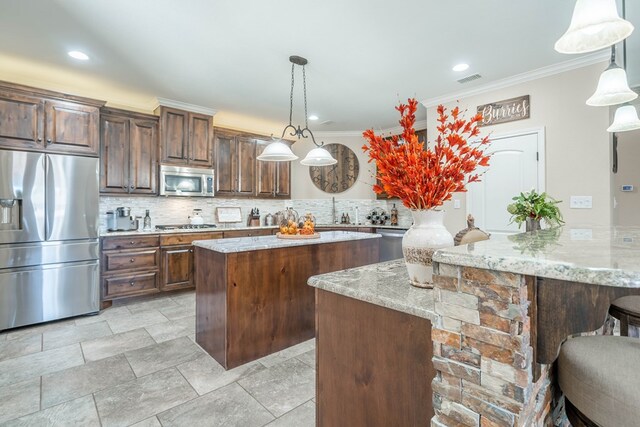 kitchen with stainless steel appliances, light stone countertops, pendant lighting, and kitchen peninsula