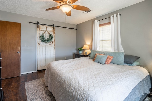 6308 S County Rd 1182, Midland, TX 79706 - bedroom featuring a barn door, a textured ceiling, visible vents, and wood finished floors