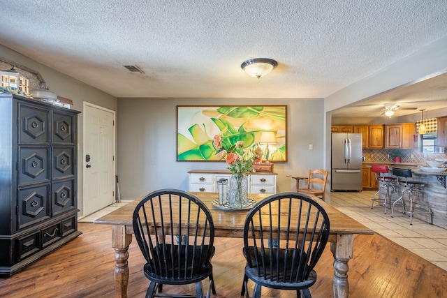 6308 S County Rd 1182, Midland, TX 79706 - dining room featuring light wood-type flooring, a textured ceiling, ceiling fan, and visible vents