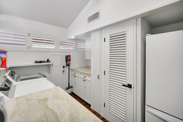 kitchen featuring visible vents, dark wood-style floors, vaulted ceiling, light countertops, and backsplash