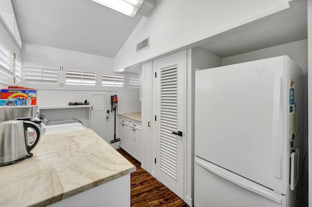 kitchen featuring visible vents, dark wood finished floors, lofted ceiling, and freestanding refrigerator