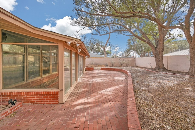 exterior space featuring a sunroom, a fenced backyard, and a patio