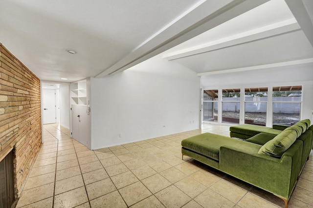 living room featuring brick wall, a fireplace, beam ceiling, and tile patterned floors