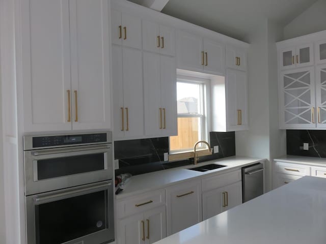 kitchen featuring white cabinets, stainless steel appliances, tasteful backsplash, and sink