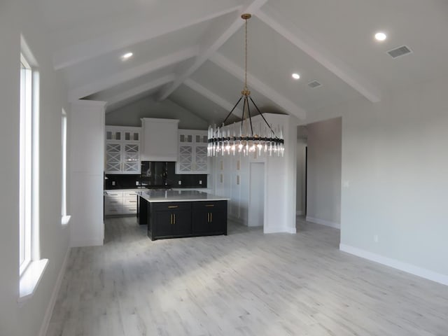 kitchen featuring a center island, hanging light fixtures, tasteful backsplash, white cabinets, and light wood-type flooring