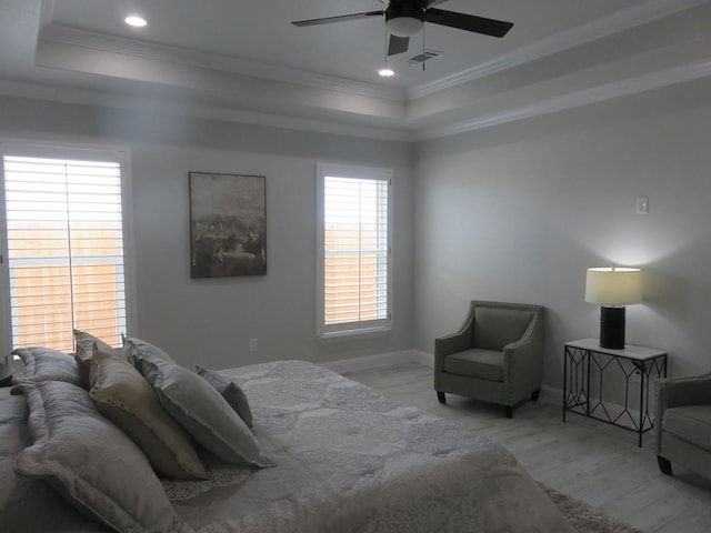 bedroom with a tray ceiling, ceiling fan, crown molding, and light hardwood / wood-style floors