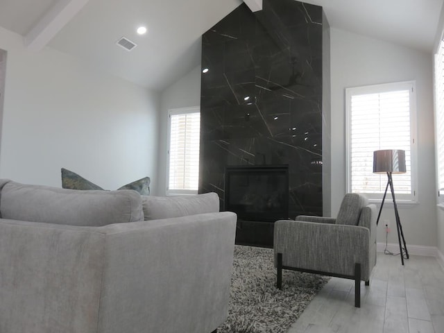 living room with hardwood / wood-style flooring, vaulted ceiling with beams, and a high end fireplace