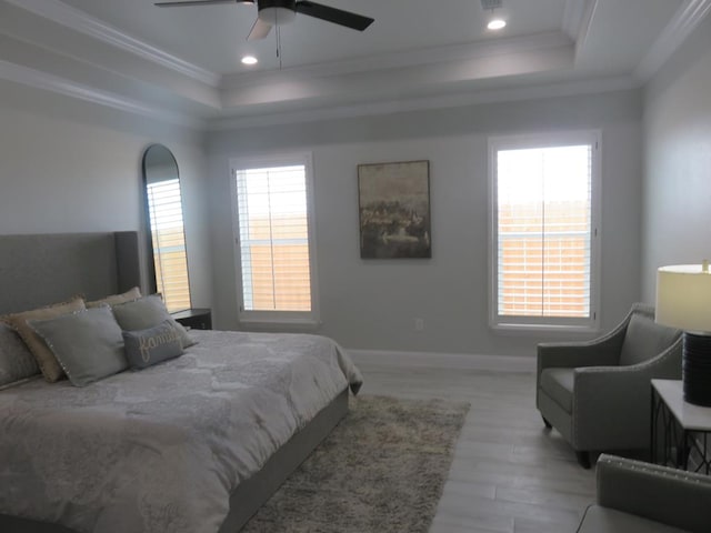 bedroom featuring light hardwood / wood-style flooring, a raised ceiling, ceiling fan, and crown molding