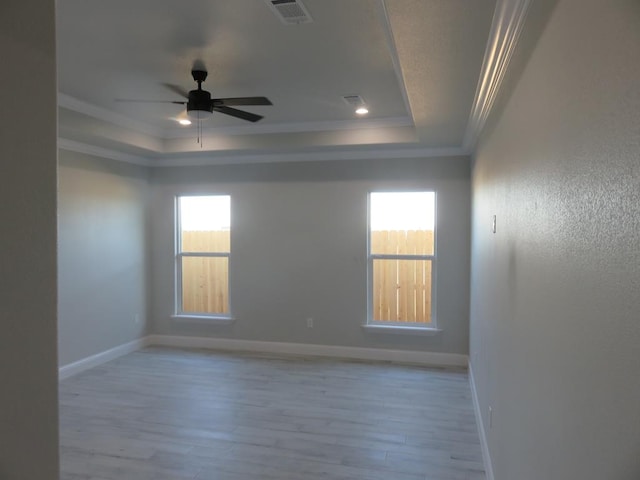 empty room with ceiling fan, a healthy amount of sunlight, crown molding, and a tray ceiling