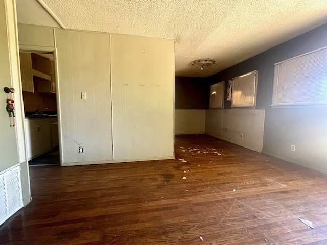 unfurnished room featuring a textured ceiling, dark hardwood / wood-style floors, and sink