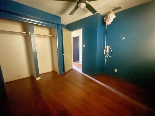 unfurnished bedroom with dark hardwood / wood-style floors, ceiling fan, and a closet