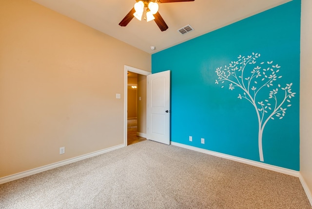 spare room with a ceiling fan, visible vents, carpet, and baseboards