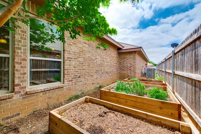 view of yard with fence, central AC unit, and a garden