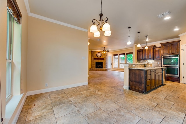 kitchen with a sink, visible vents, baseboards, an inviting chandelier, and ornamental molding
