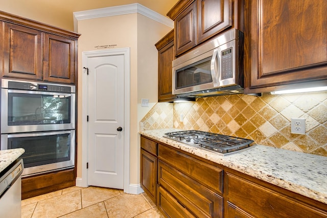 kitchen featuring backsplash, appliances with stainless steel finishes, and light stone counters
