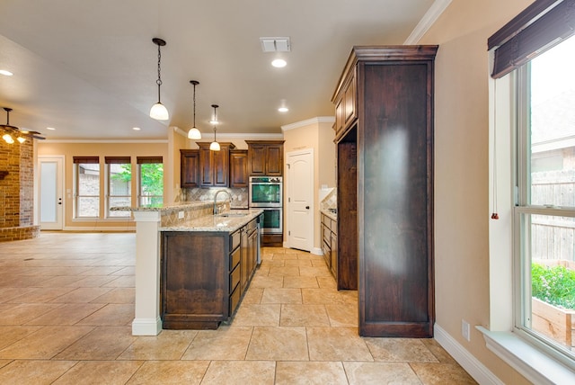 kitchen featuring light stone counters, double oven, a sink, visible vents, and crown molding