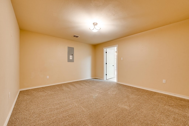 carpeted spare room featuring visible vents, electric panel, and baseboards
