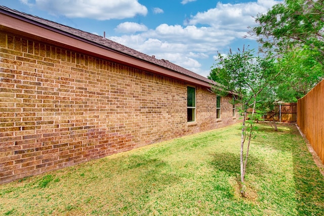 view of property exterior featuring a yard, a fenced backyard, and brick siding
